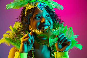 Image showing Beautiful young woman in carnival and masquerade costume on gradient studio background in neon light