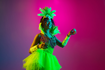 Image showing Beautiful young woman in carnival and masquerade costume on gradient studio background in neon light