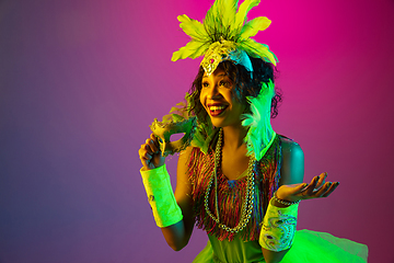 Image showing Beautiful young woman in carnival and masquerade costume on gradient studio background in neon light