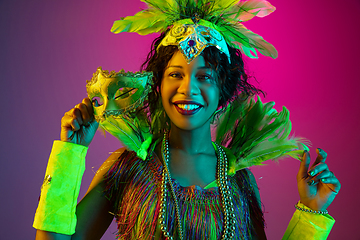 Image showing Beautiful young woman in carnival and masquerade costume on gradient studio background in neon light