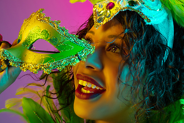 Image showing Beautiful young woman in carnival and masquerade costume on gradient studio background in neon light