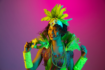 Image showing Beautiful young woman in carnival and masquerade costume on gradient studio background in neon light