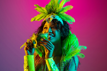 Image showing Beautiful young woman in carnival and masquerade costume on gradient studio background in neon light