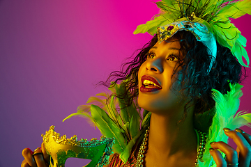 Image showing Beautiful young woman in carnival and masquerade costume on gradient studio background in neon light