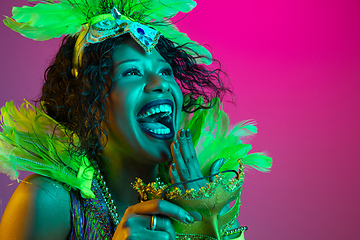 Image showing Beautiful young woman in carnival and masquerade costume on gradient studio background in neon light