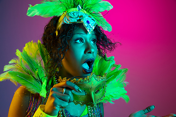 Image showing Beautiful young woman in carnival and masquerade costume on gradient studio background in neon light