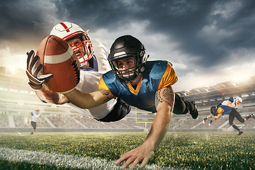 Image showing American football players in fight for goal at stadium in flashlights. Professional sportsman during game playing in action and motion.