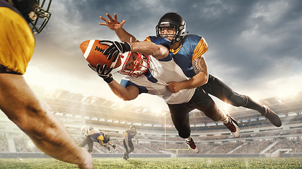 Image showing American football players in fight for goal at stadium in flashlights. Professional sportsman during game playing in action and motion.