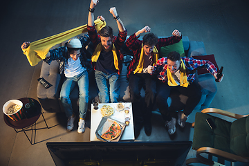 Image showing Group of friends watching TV, sport match together. Emotional fans cheering for favourite team. Top view. Concept of friendship, leisure activity, emotions