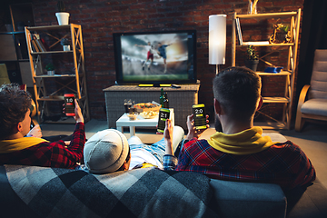 Image showing Group of friends watching TV, sport match together. Emotional fans cheering for favourite team, watching on exciting game. Concept of friendship, leisure activity, emotions