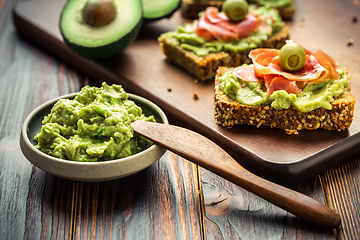 Image showing Guacamole dip or spread with open sandwiches and ham on wooden kitchen table