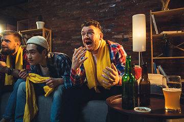 Image showing Group of friends watching TV, sport match together. Emotional fans cheering for favourite team, watching on exciting game. Concept of friendship, leisure activity, emotions