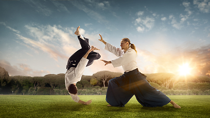 Image showing Man and boy, teacher fighting Aikido, training martial arts on meadow in summer evening