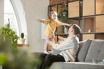 Image showing Happy father and little cute daughter at home. Family time, togehterness, parenting and happy childhood concept. Weekend with sincere emotions.