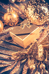 Image showing Christmas ornaments with small present in golden tones