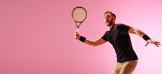 Image showing Young caucasian man playing tennis isolated on pink studio background, action and motion concept