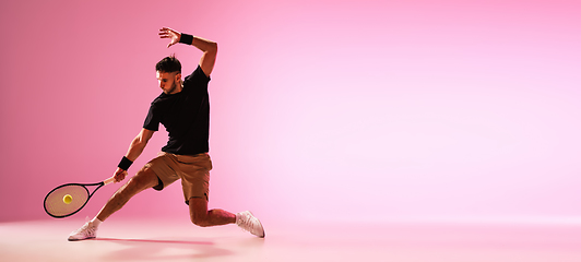 Image showing Young caucasian man playing tennis isolated on pink studio background, action and motion concept