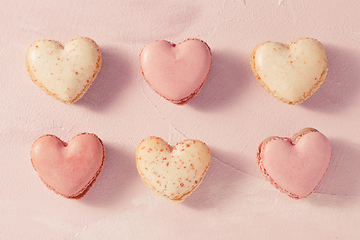 Image showing Delicious French macarons in heart shape on pink background