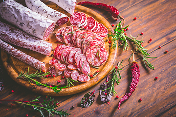 Image showing Charcuterie - Assortment of air-dried salami and sausage on wooden cutting board with spices