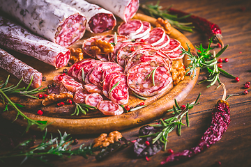 Image showing Charcuterie - Assortment of air-dried salami and sausage on wooden cutting board with spices