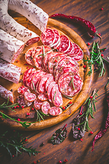 Image showing Charcuterie - Assortment of air-dried salami and sausage on wooden cutting board with spices