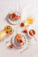 Image showing Small canape snack, crostini with ham, fig and apple wine