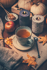 Image showing Hot tea with cookies, apple and fall foliage and pumpkins on wooden background