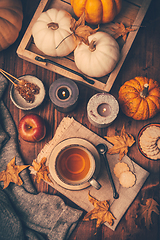 Image showing Hot tea with cookies, apple and fall foliage and pumpkins on wooden background