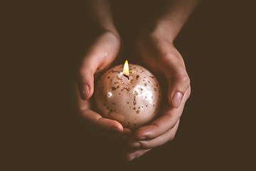 Image showing Hands holding Christmas candle on dark background