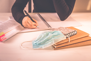 Image showing Detail of hands writing with school supplies and protective mask