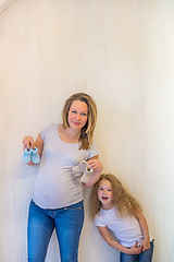 Image showing Pregnant woman holding blue baby booties with her daughter