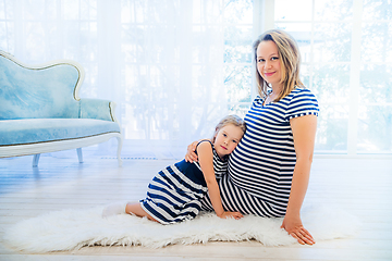 Image showing Beautiful pregnant woman with daughter sitting near the window