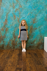 Image showing Cute girl in striped clothes standing near the wall