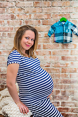 Image showing Beautiful pregnant woman sitting near the brick wall