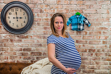 Image showing Beautiful pregnant woman sitting near the brick wall