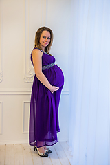 Image showing Beautiful pregnant woman in an ultraviolet dress standing near the window