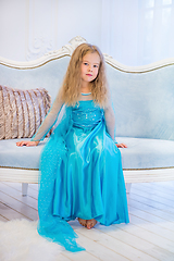 Image showing Cute girl in a fancy dress sitting on the sofa