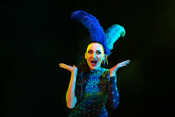 Image showing Beautiful young woman in carnival and masquerade costume in colorful neon lights on black background