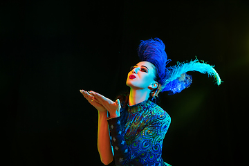 Image showing Beautiful young woman in carnival and masquerade costume in colorful neon lights on black background