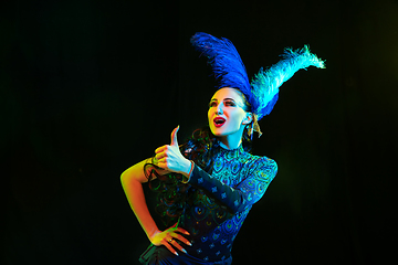 Image showing Beautiful young woman in carnival and masquerade costume in colorful neon lights on black background