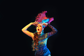 Image showing Beautiful young woman in carnival and masquerade costume in colorful neon lights on black background