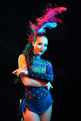 Image showing Beautiful young woman in carnival and masquerade costume in colorful neon lights on black background