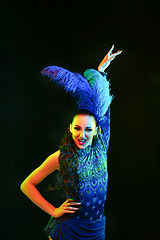 Image showing Beautiful young woman in carnival and masquerade costume in colorful neon lights on black background