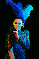 Image showing Beautiful young woman in carnival and masquerade costume in colorful neon lights on black background