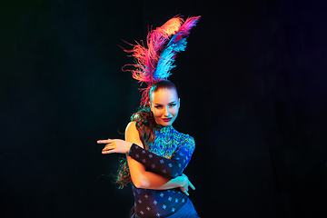 Image showing Beautiful young woman in carnival and masquerade costume in colorful neon lights on black background