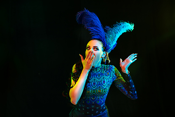 Image showing Beautiful young woman in carnival and masquerade costume in colorful neon lights on black background