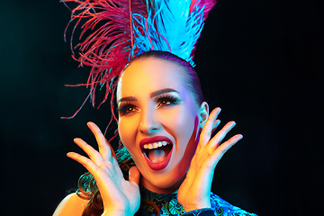 Image showing Beautiful young woman in carnival and masquerade costume in colorful neon lights on black background