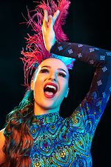 Image showing Beautiful young woman in carnival and masquerade costume in colorful neon lights on black background