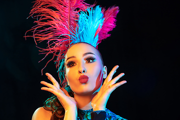 Image showing Beautiful young woman in carnival and masquerade costume in colorful neon lights on black background