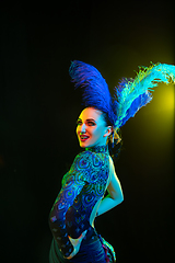 Image showing Beautiful young woman in carnival and masquerade costume in colorful neon lights on black background